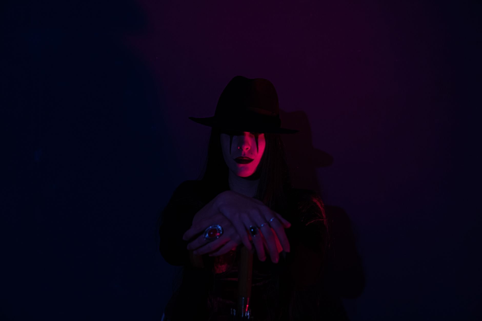 A mysterious figure wearing a black hat, half-revealed in darkness